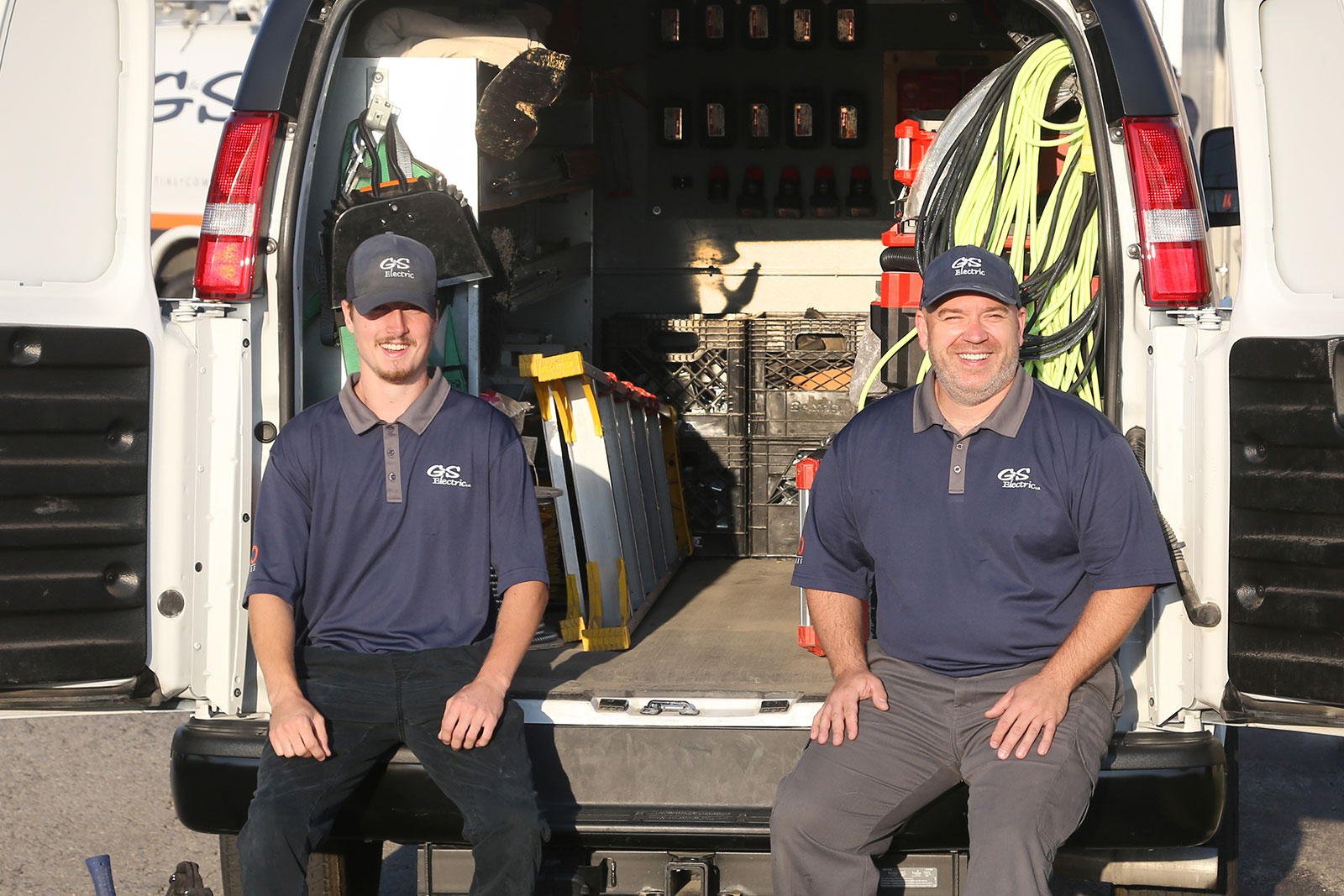 Two G&S electricians in London Ontario sitting on van's door.